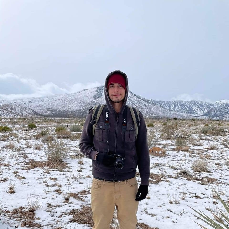 Cesar standing outdoors in the snowy desert near Las Vegas with mountains behind him